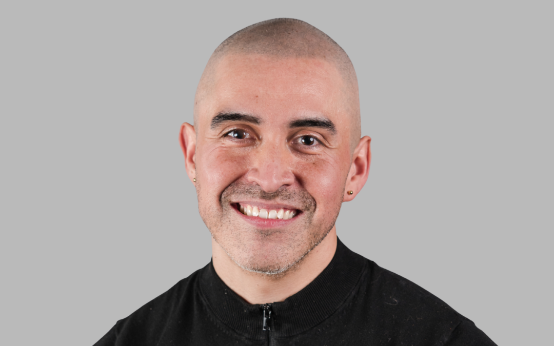 Bald-headed man wearing a black shirt, looking at the camera
