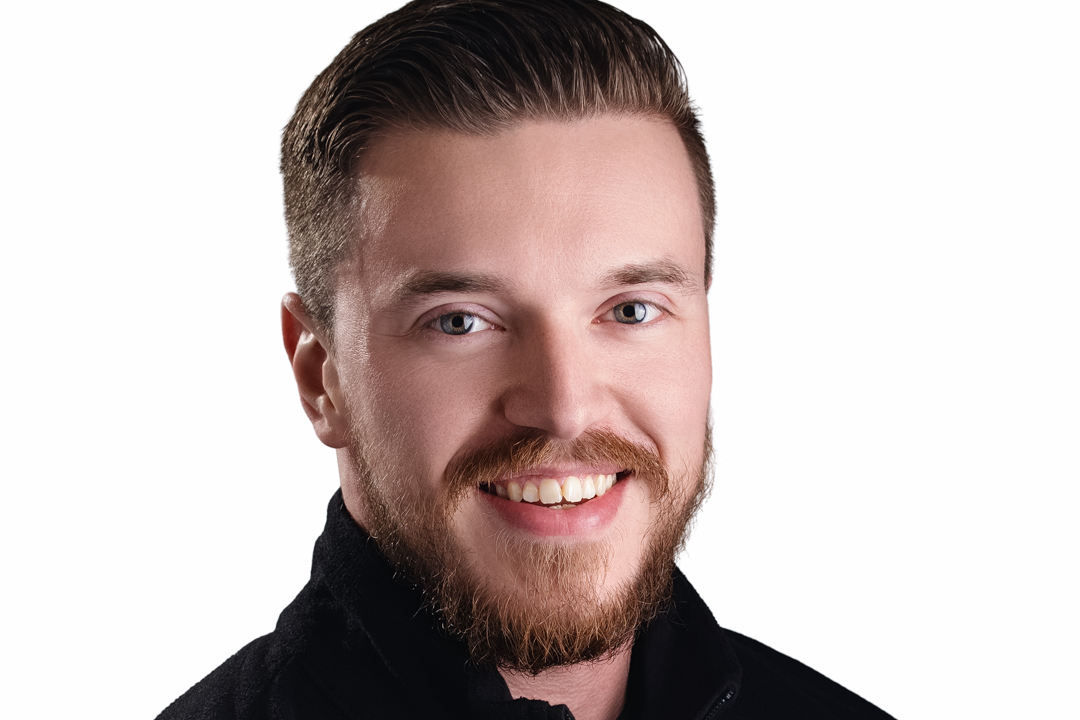 Vestacon_Vaughan_052025 -1_(2) Smiling woman with long dark hair, wearing a red blazer and a gold necklace with a cross pendant, against a black background.